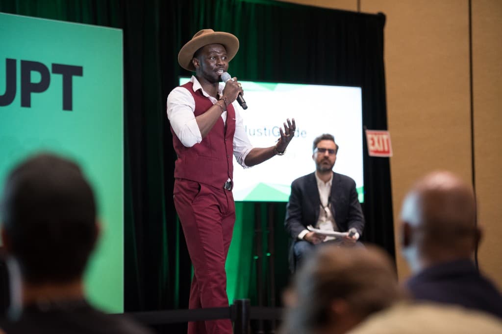 Bisi Obateru on stage at TechCrunch Disrupt with the JustiGuide screen